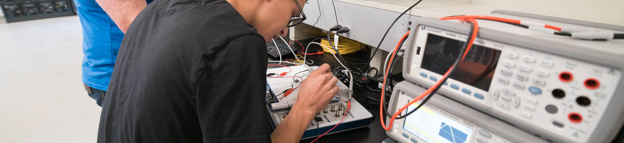 Estudiante realizando investigación en laboratorio de ingeniería eléctrica