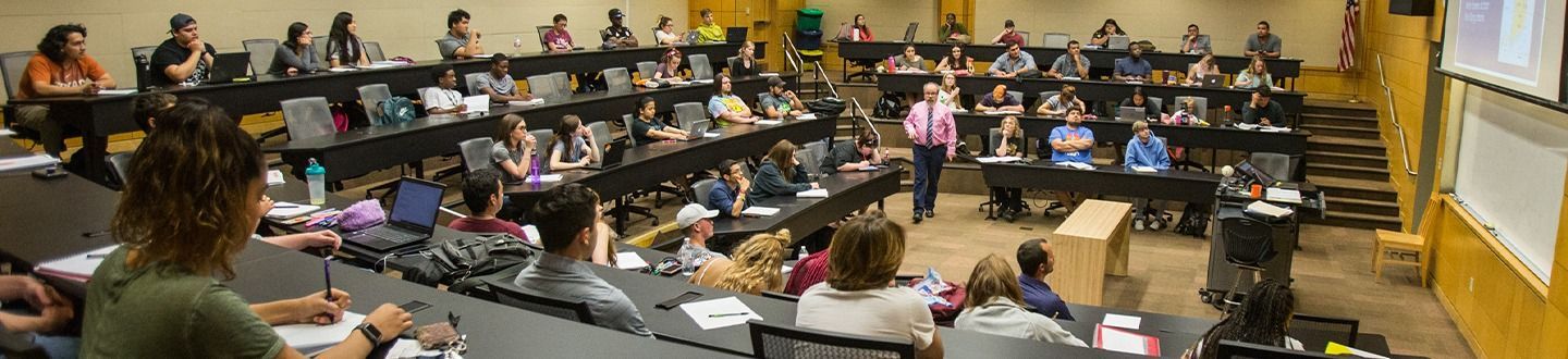 Auditorium style classroom with students listening to the professor