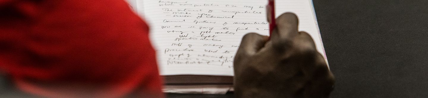 Estudiante sentado en un escritorio tomando notas durante la clase