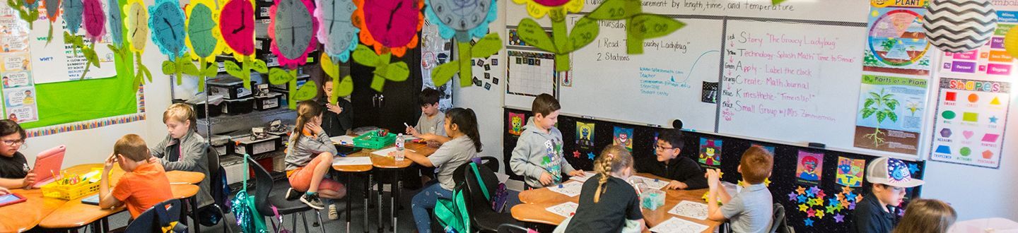 Estudiantes de primaria sentados en sus pupitres en un aula trabajando en un proyecto