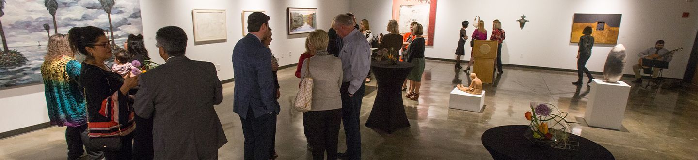 Inauguración de la galería con personas reunidas mirando obras de arte