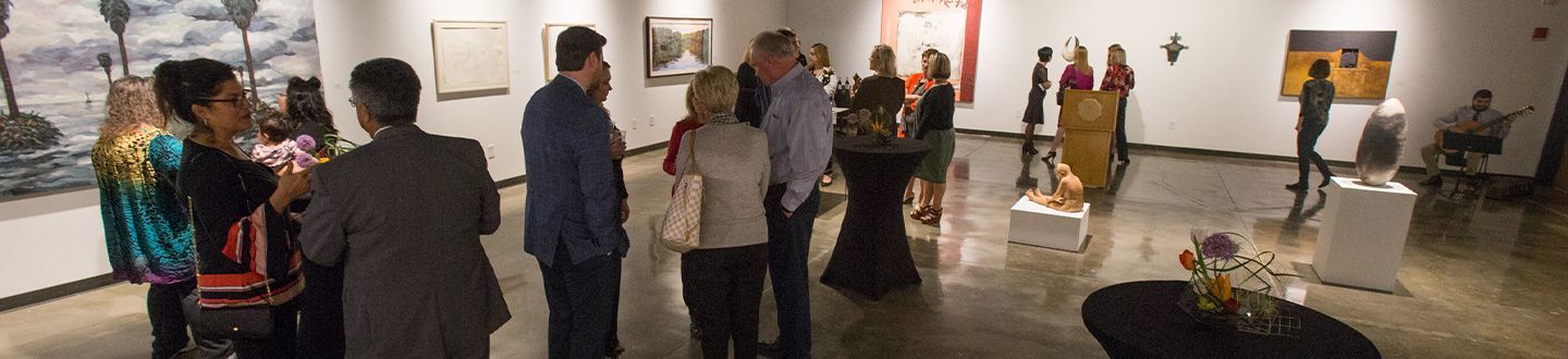 Gallery opening with people gathered looking at art pieces