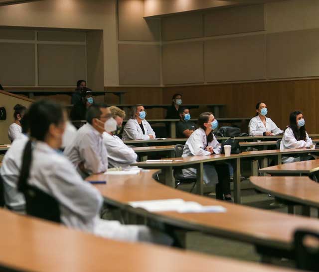 Estudiantes reunidos alrededor de una computadora.