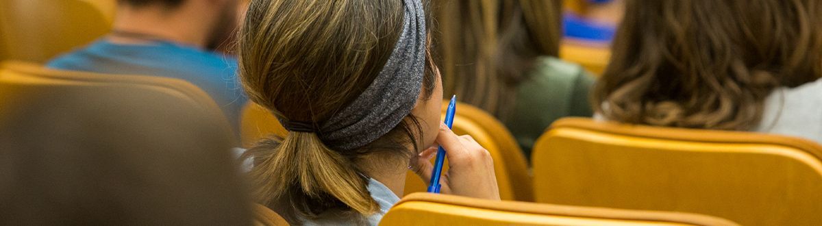 Estudiantes sentados en el auditorio escuchando al profesor