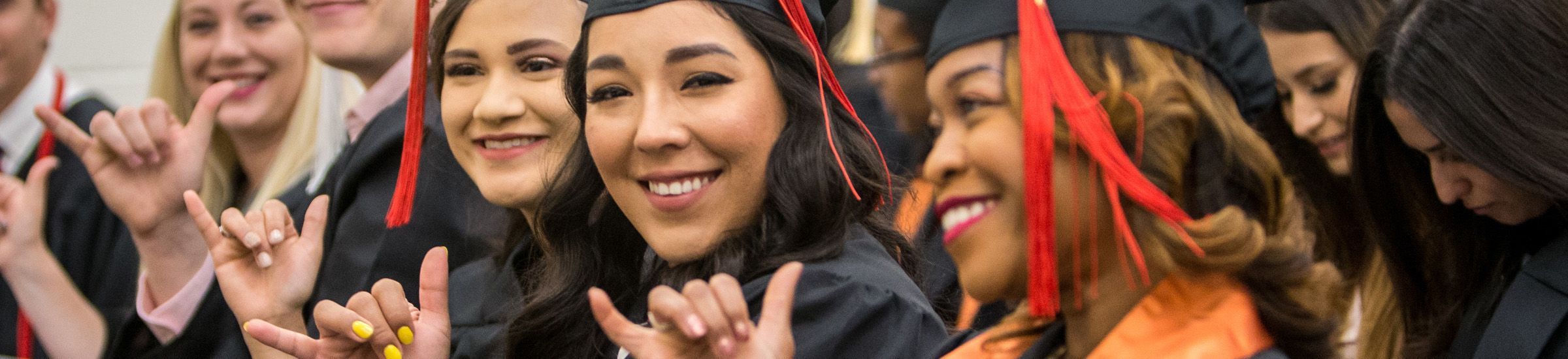 graduates doing the falcons up hand sign waiting in line to graduate