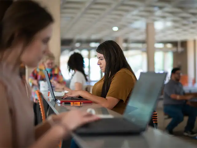 Estudiante que trabaja en una computadora portátil en la biblioteca