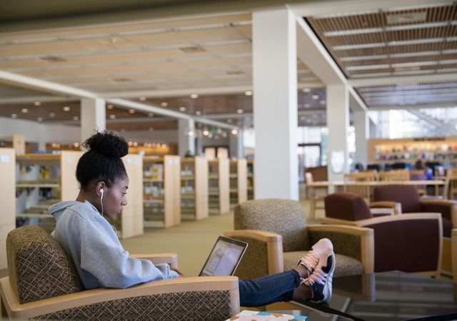 Estudiante que trabaja en una computadora portátil en la biblioteca