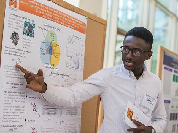 Estudiante señalando un tablero de investigación durante la presentación