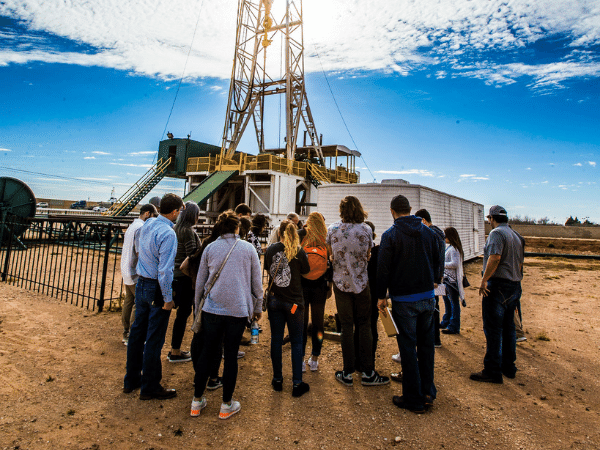 Estudiantes cerca de la plataforma petrolera tomando notas