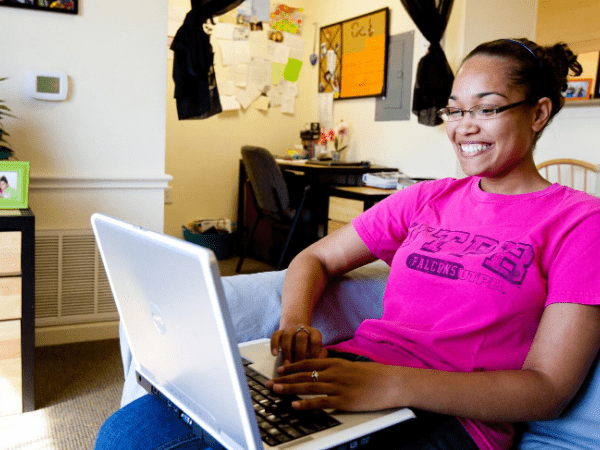 Estudiante que estudia en la computadora en el dormitorio