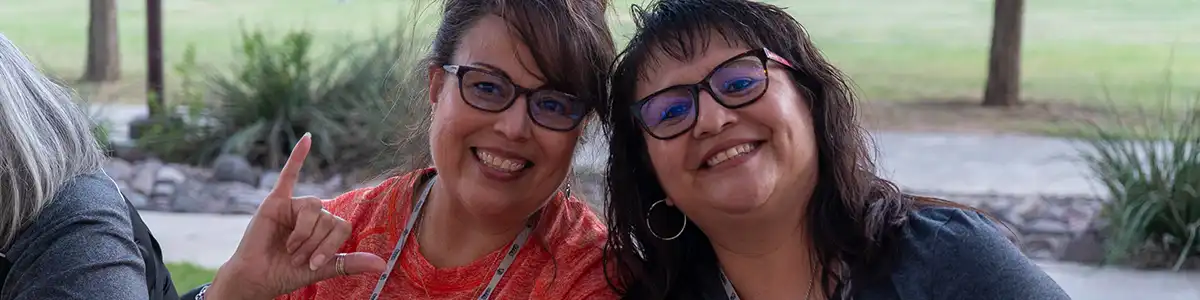 Two UTPB students smiling with falcons up