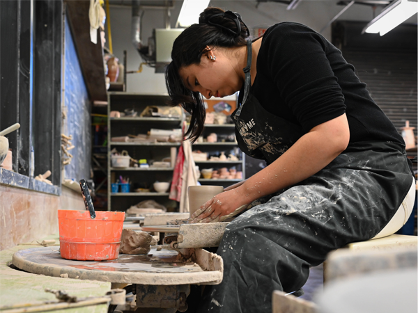 Image of a student throwing clay on the pottery wheel.