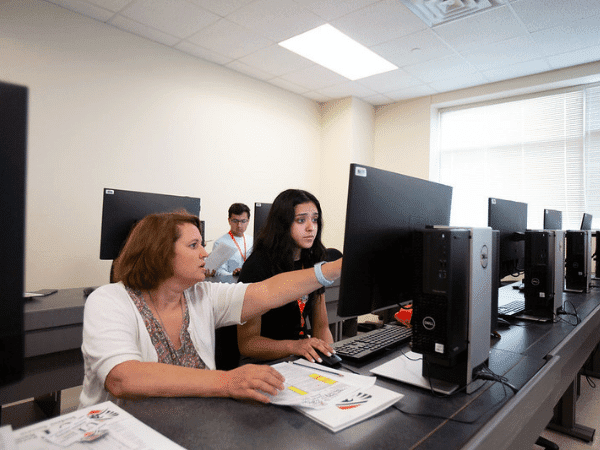 Miembro de la facultad ayudando a los estudiantes en la computadora