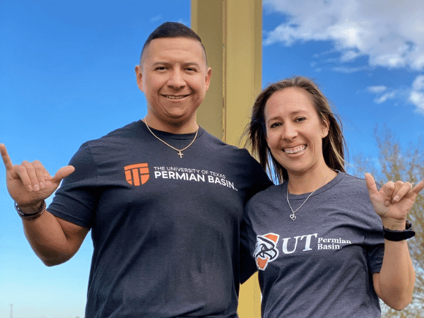 Dos exalumnos sonriendo para la cámara levantando sus Falcons