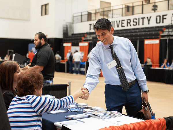 Estudiante estrechando la mano de los empleadores en la feria de empleo