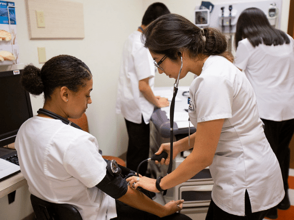 Estudiante de enfermería tomando la presión arterial a otro estudiante de enfermería
