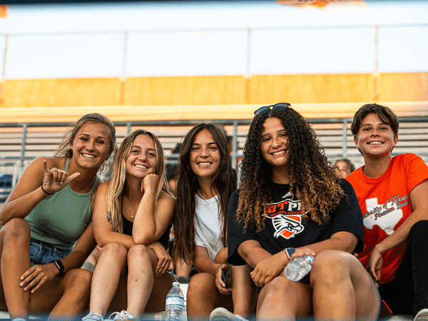 estudiantes sentados en gradas en el juego de fútbol