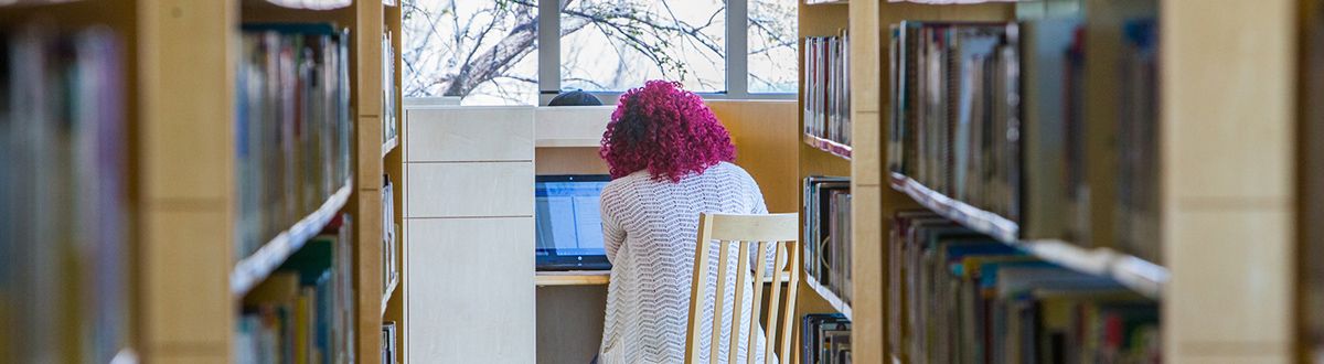 Student writing in a library cubicle