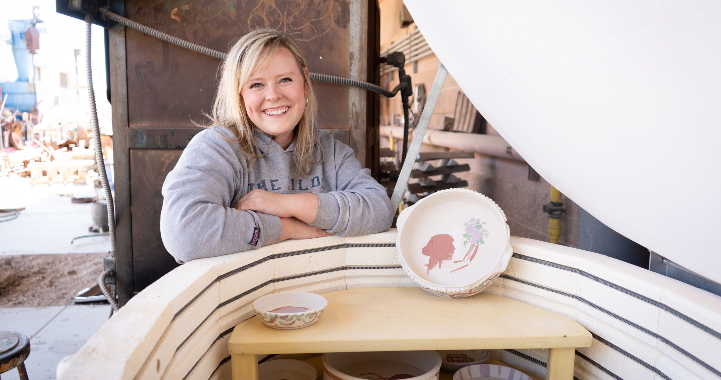 Emily Daw posing with her ceramics pieces 