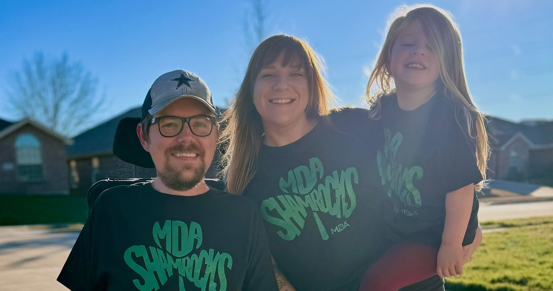 Matt Plummer smiling for a picture with his wife and daughter wearing the MDA shirts he designed