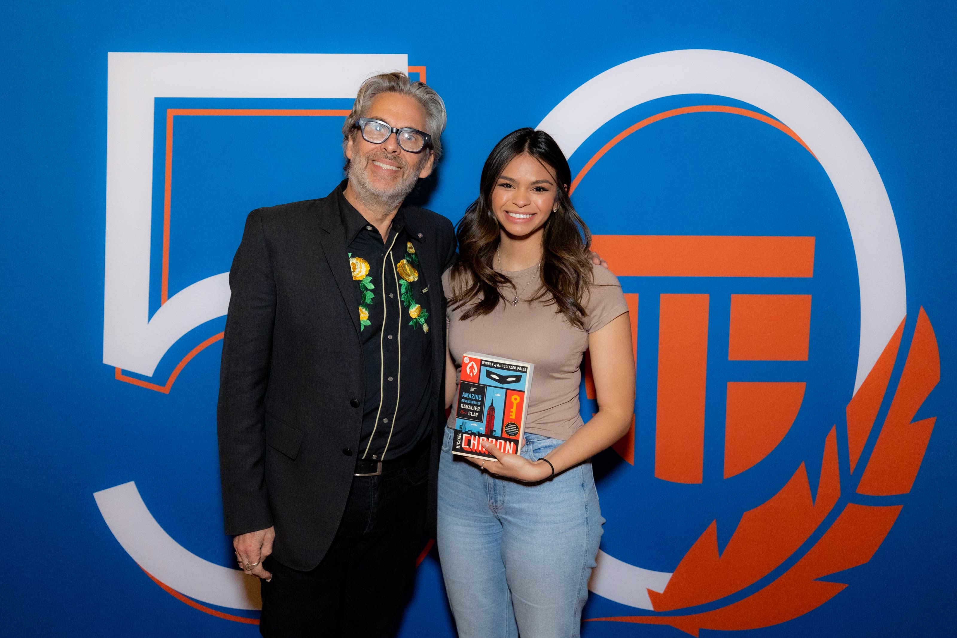 Michael Chabon posing next to book with a UTPB student