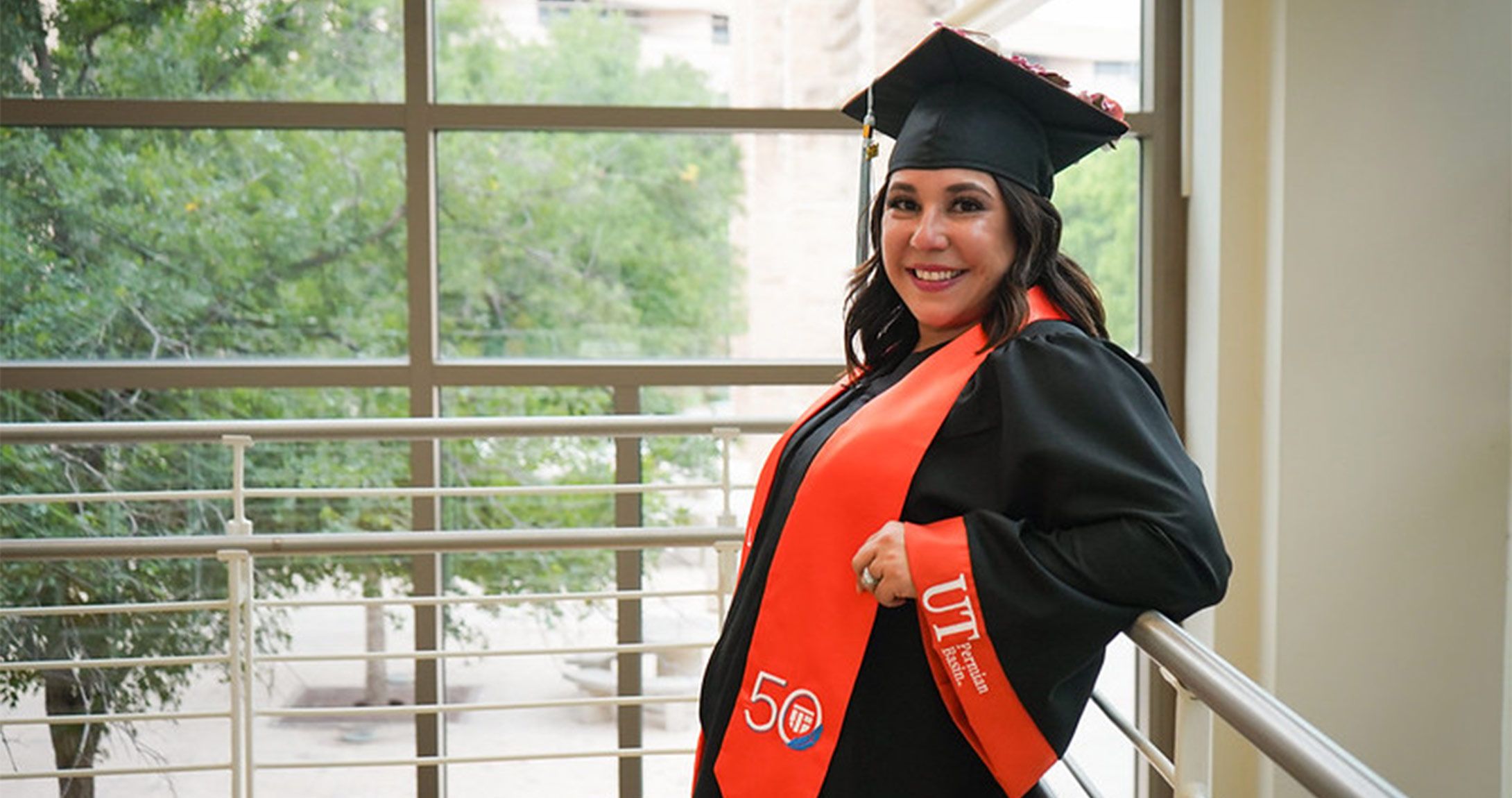 UTPB spring graduate poses in cap and gown 