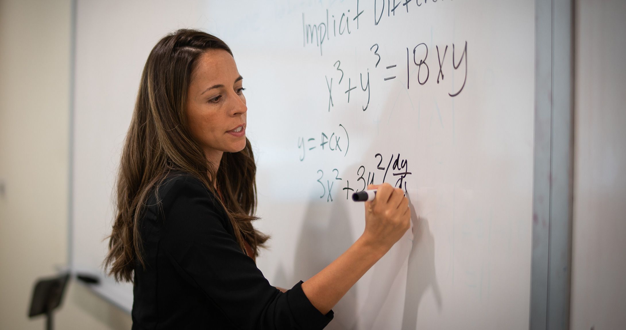 Wendy Padilla writing math equation on white board in classroom