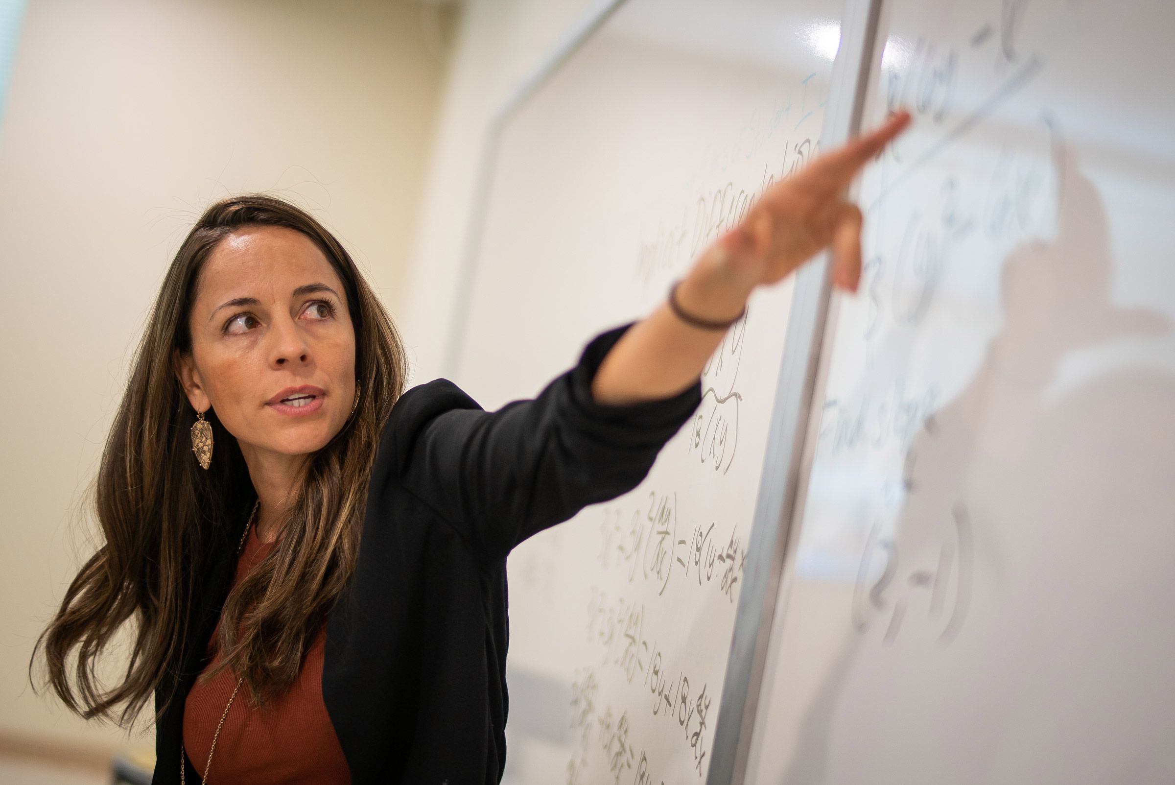 Wendy Padilla pointing at white board with math problem in classroom