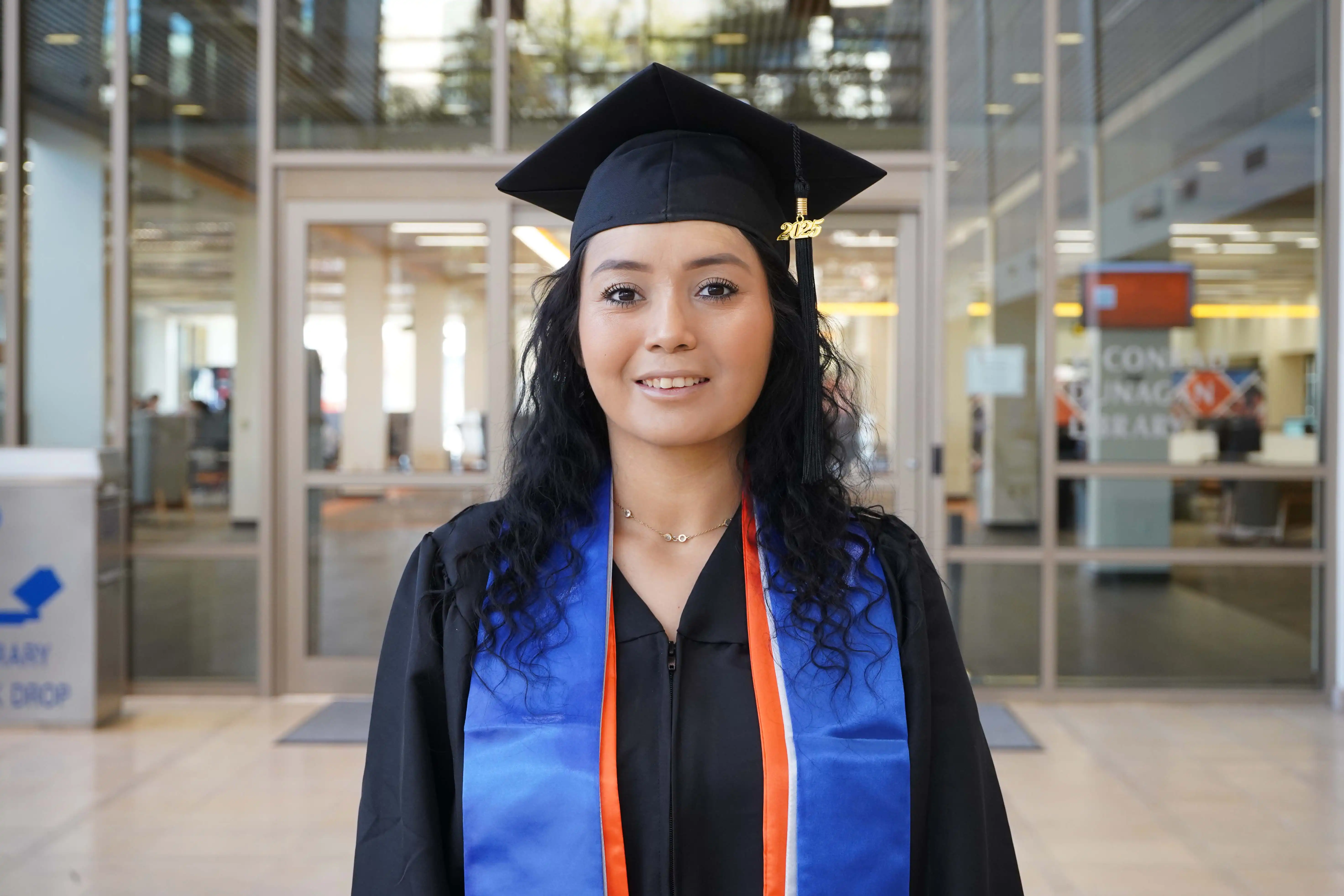 Kassandra Valencia, UTPB graduate, standing in the on-campus library foyer. 