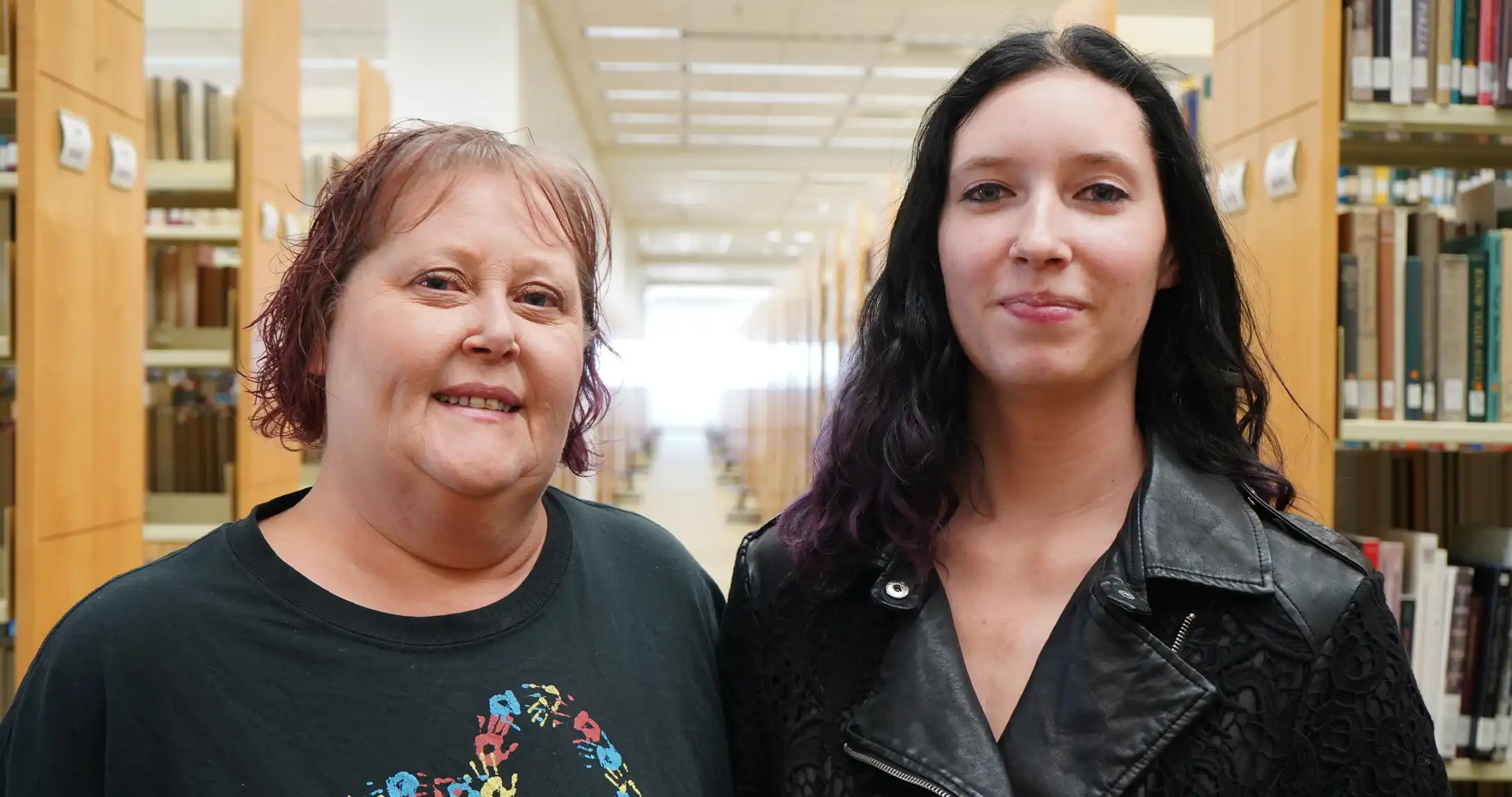 Janice and Mady Campbell standing in the on-campus library. 