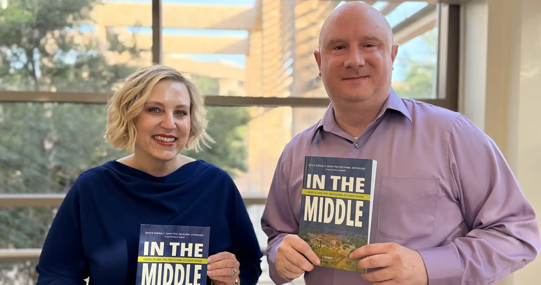 Becky Spurlock (left) and Corey Benson (right) holding the book with their co-authored chapter inside. 