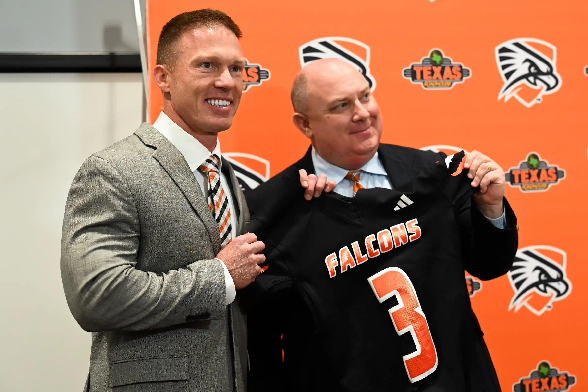 Coach Softley with VP for Athletics, Scott Larson, holding up a Falcons jersey. 