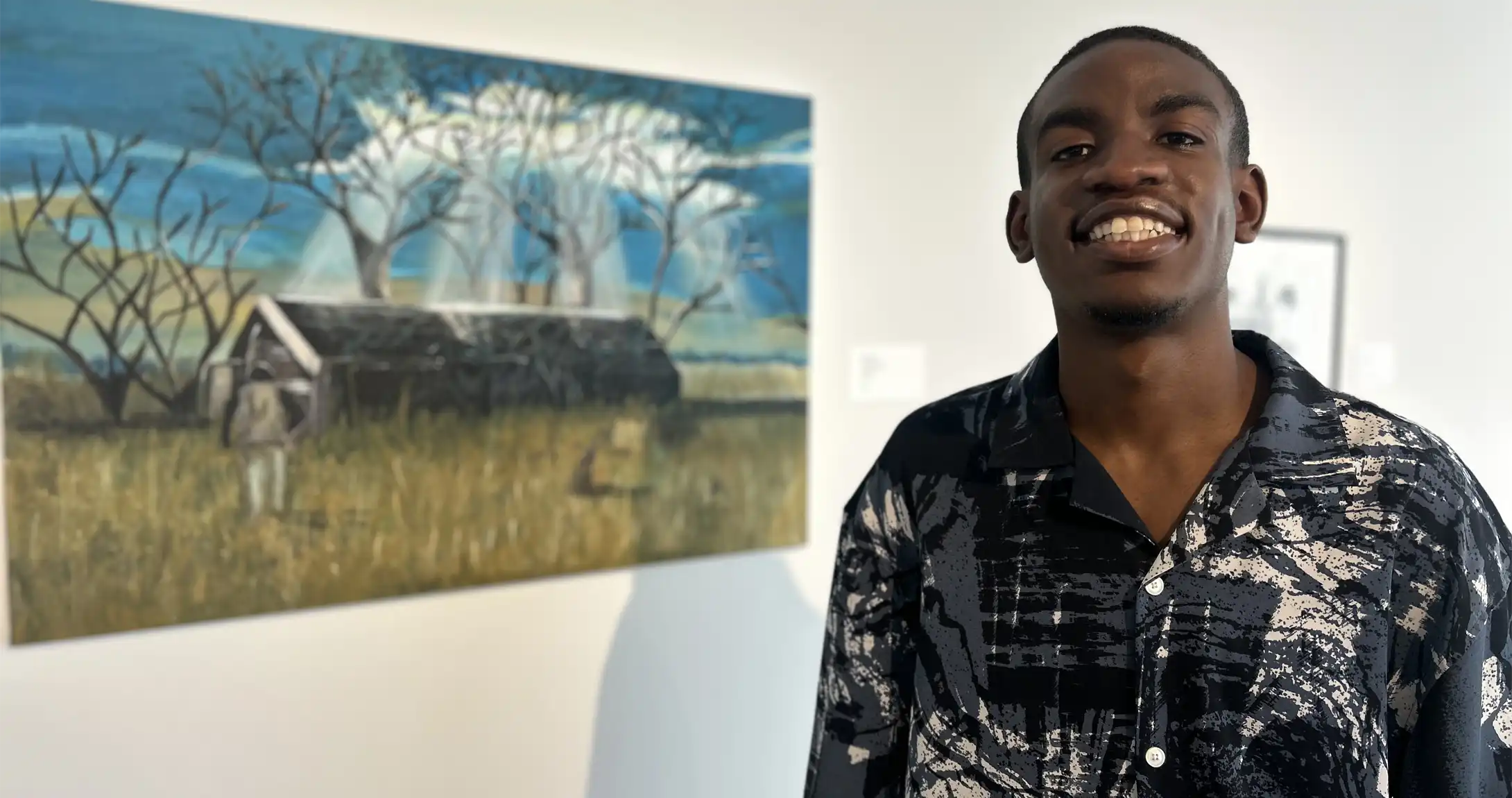 Elijah Givens standing in front of his artwork that is displayed at the Ellen Noel Art Museum. 