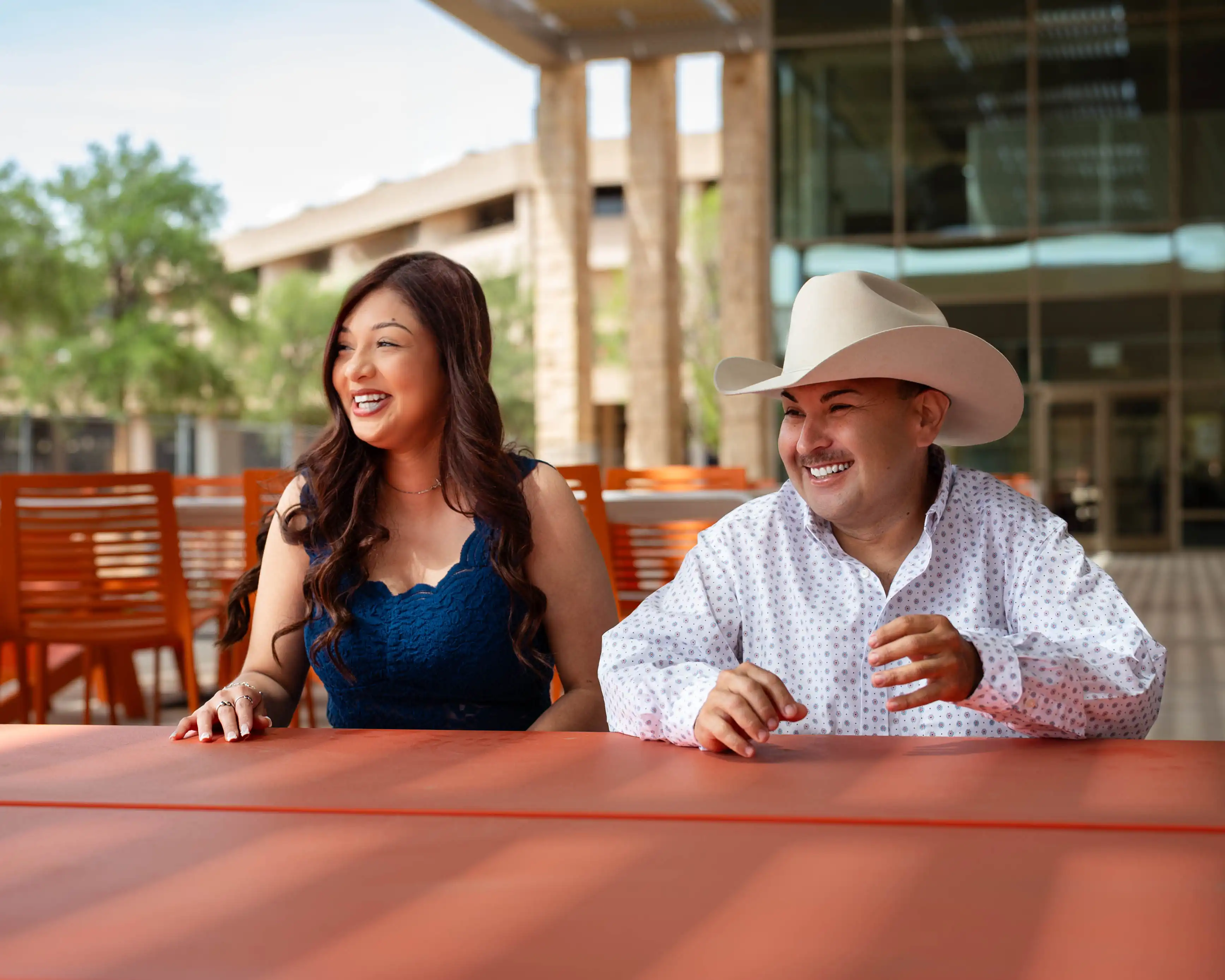 Stephanie and Christian laughing at a table outside of the Student Activities Center. 