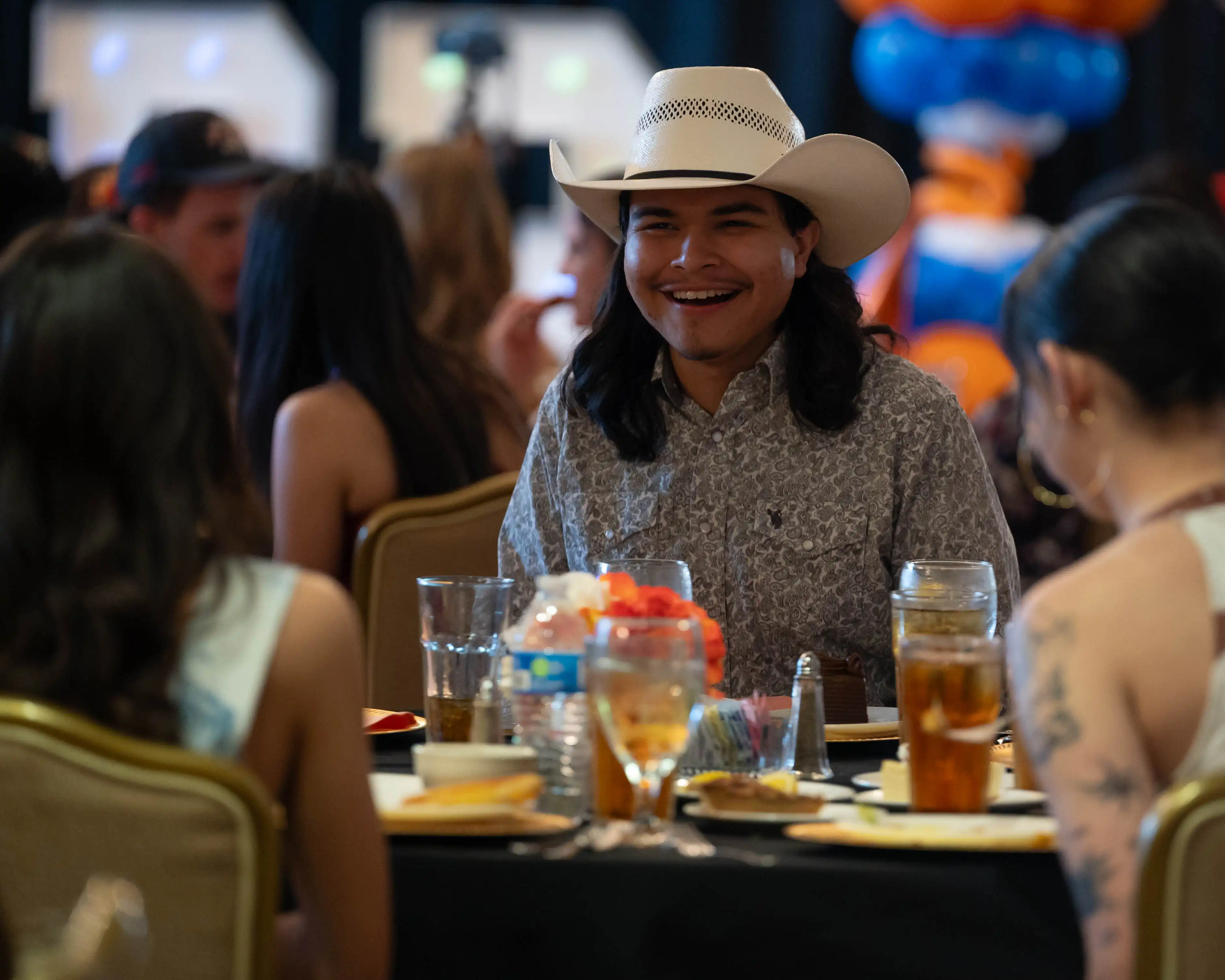 A UTPB student at a table during the Freddy awards laughing with the other people seated at the table. 