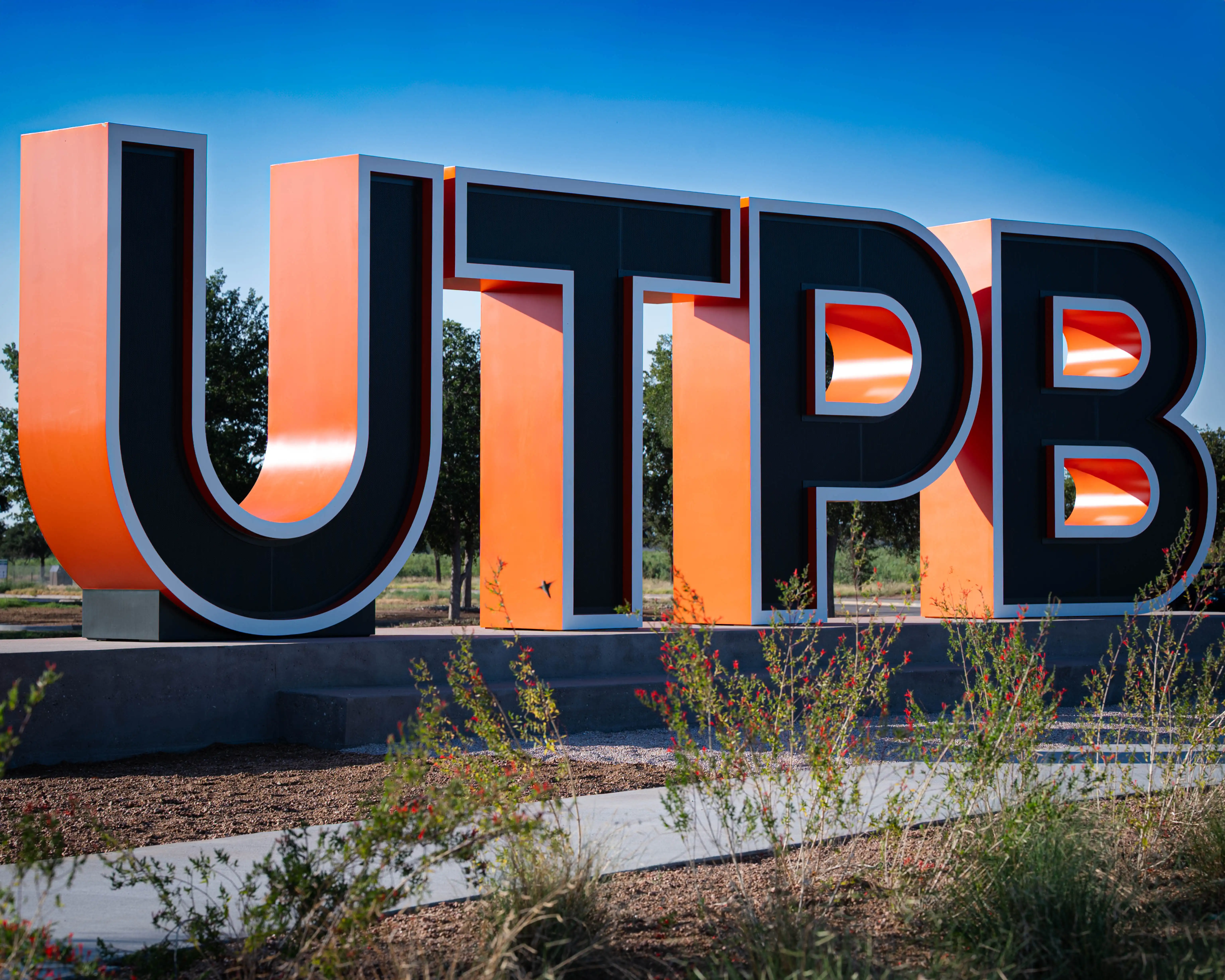 Large UTPB letters made with orange, black, and white steel that light up at night. 