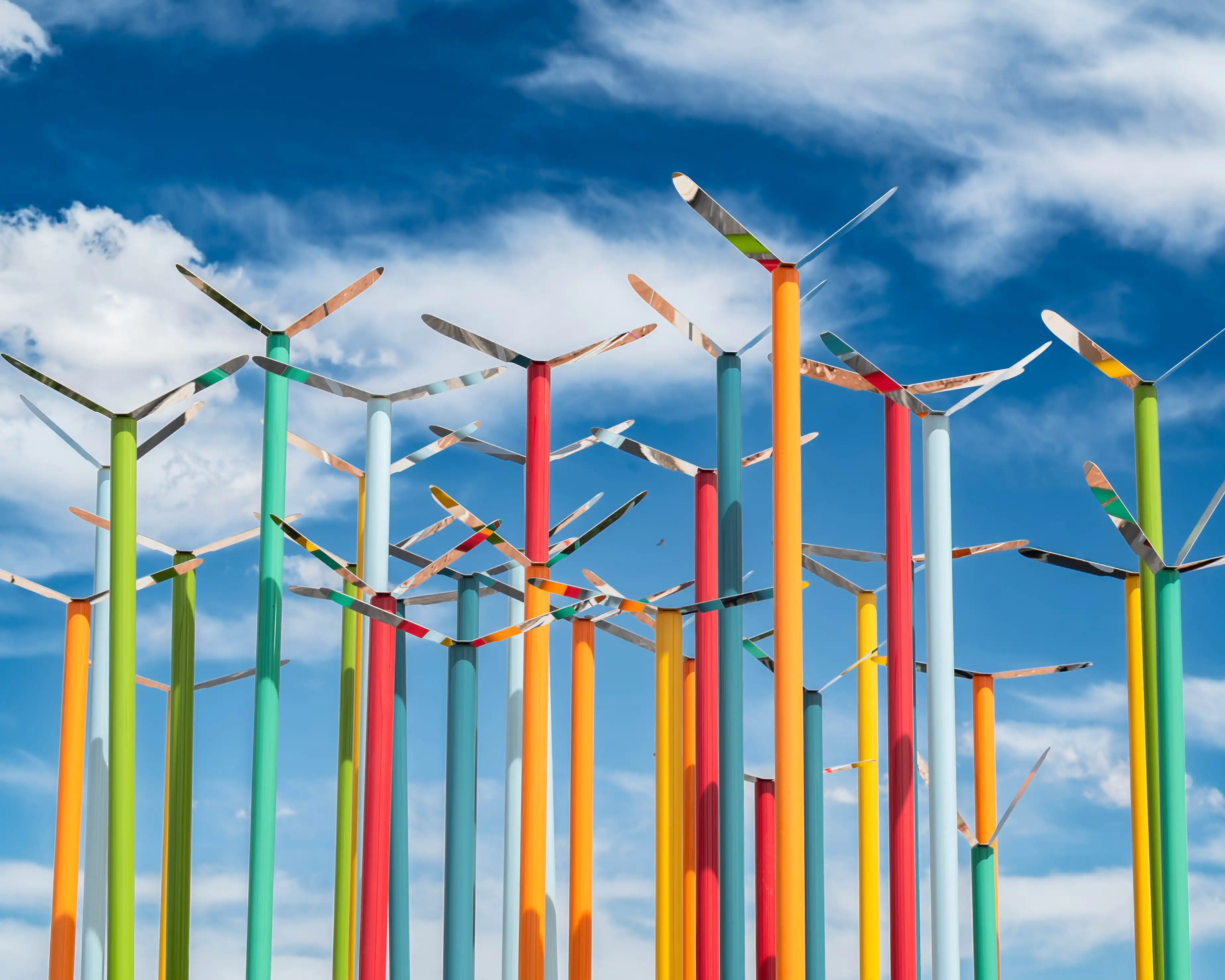 A variety of colorful metal poles with the mirrored metal birds on top.