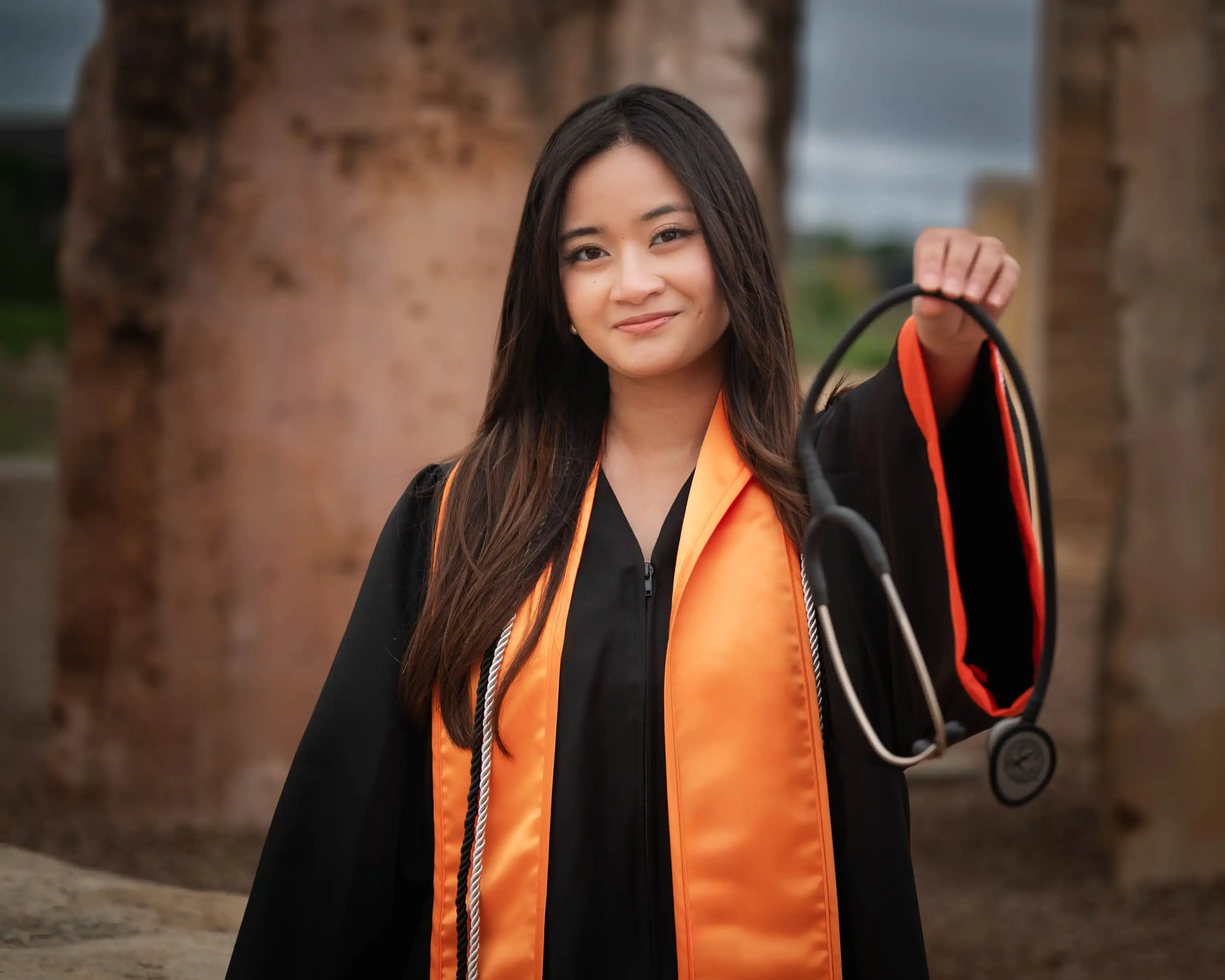 Nadine Marcelo dressed in her UTPB regalia while holding a stethoscope in front of the camera. 