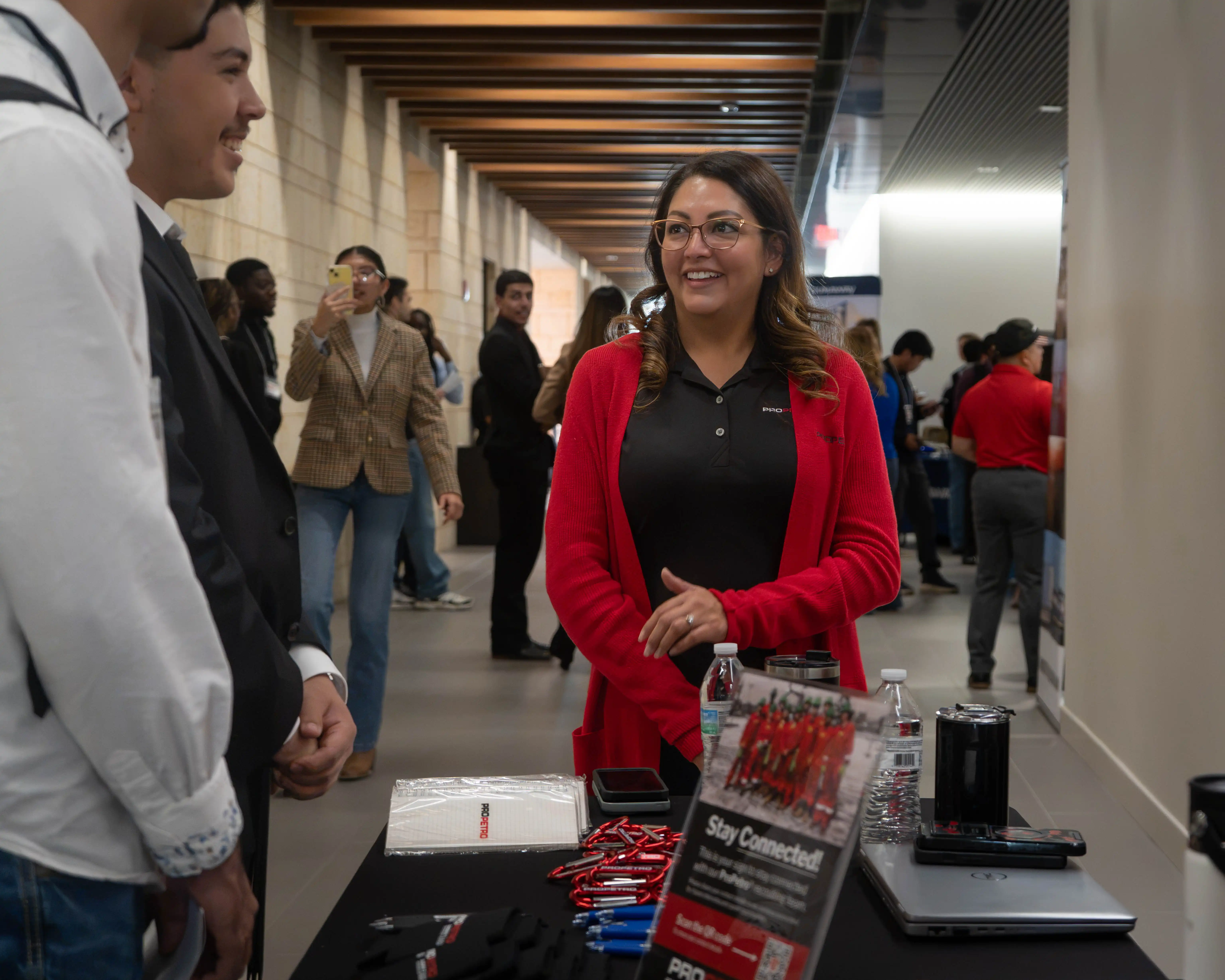 A recruiter from ProPetro speaking to a UTPB engineering student during the Engineering Internship Fair  with the photo of the summer 2026 interns on the table. 