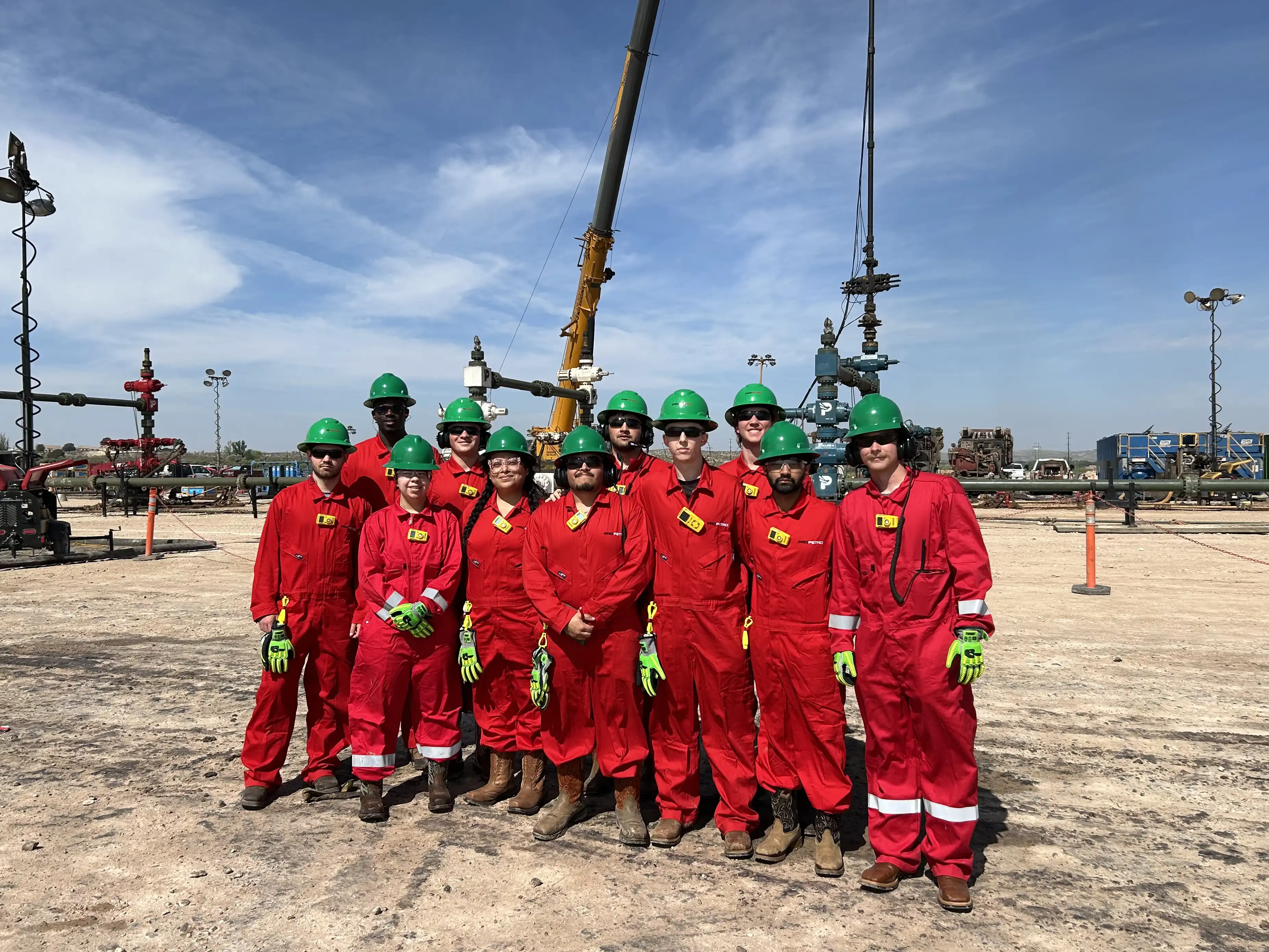 The ProPetro summer 2026 interns dressed in their fire retardant gear in front of a well pad. 