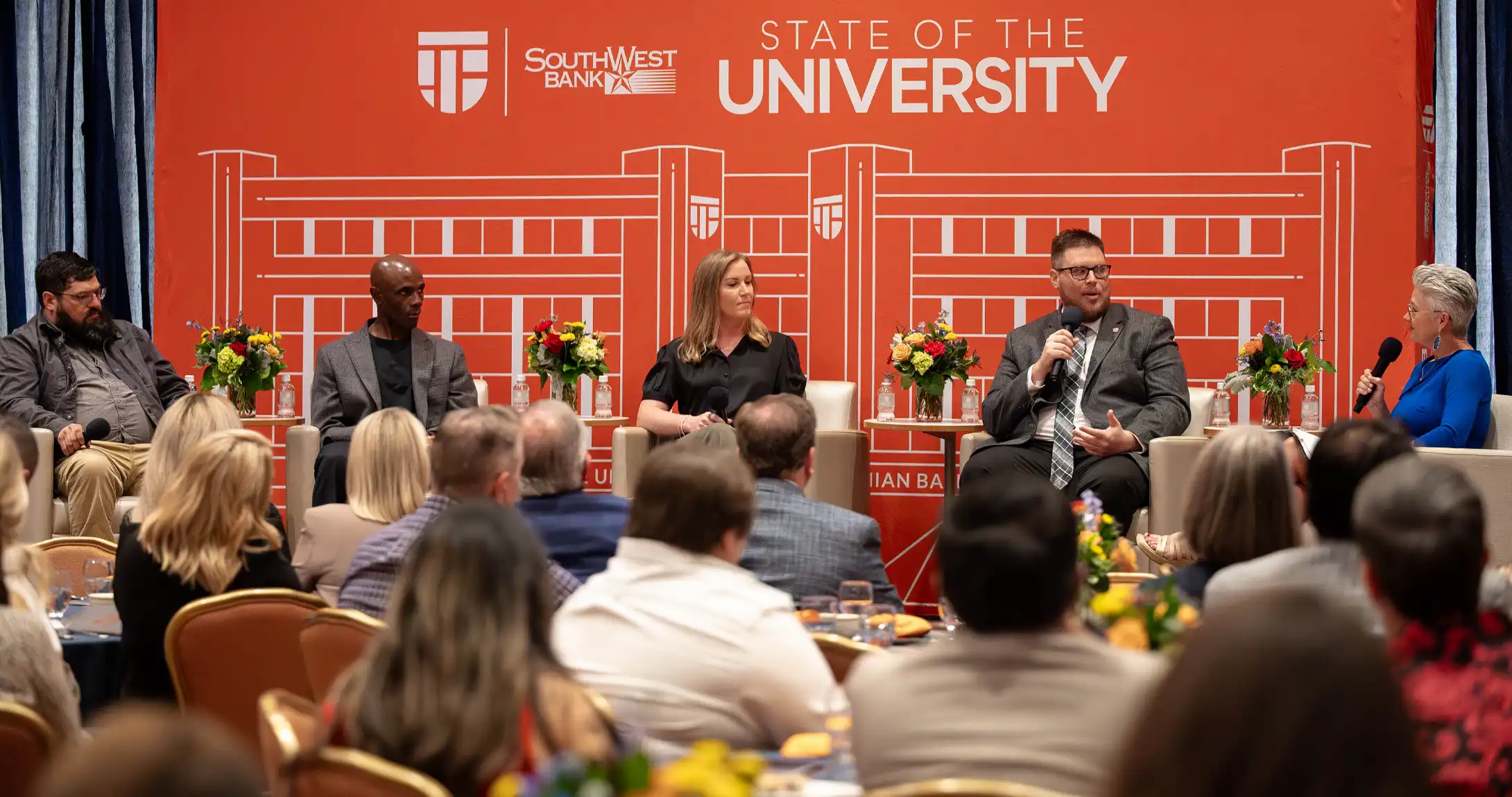 Dr. Woodley speaking with a panel on stage at the 2026 State of the University. 