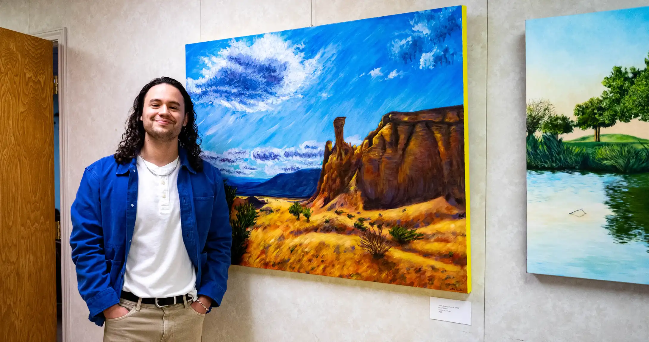 A photo of artist Talon Cress standing next to one of his pieces. 