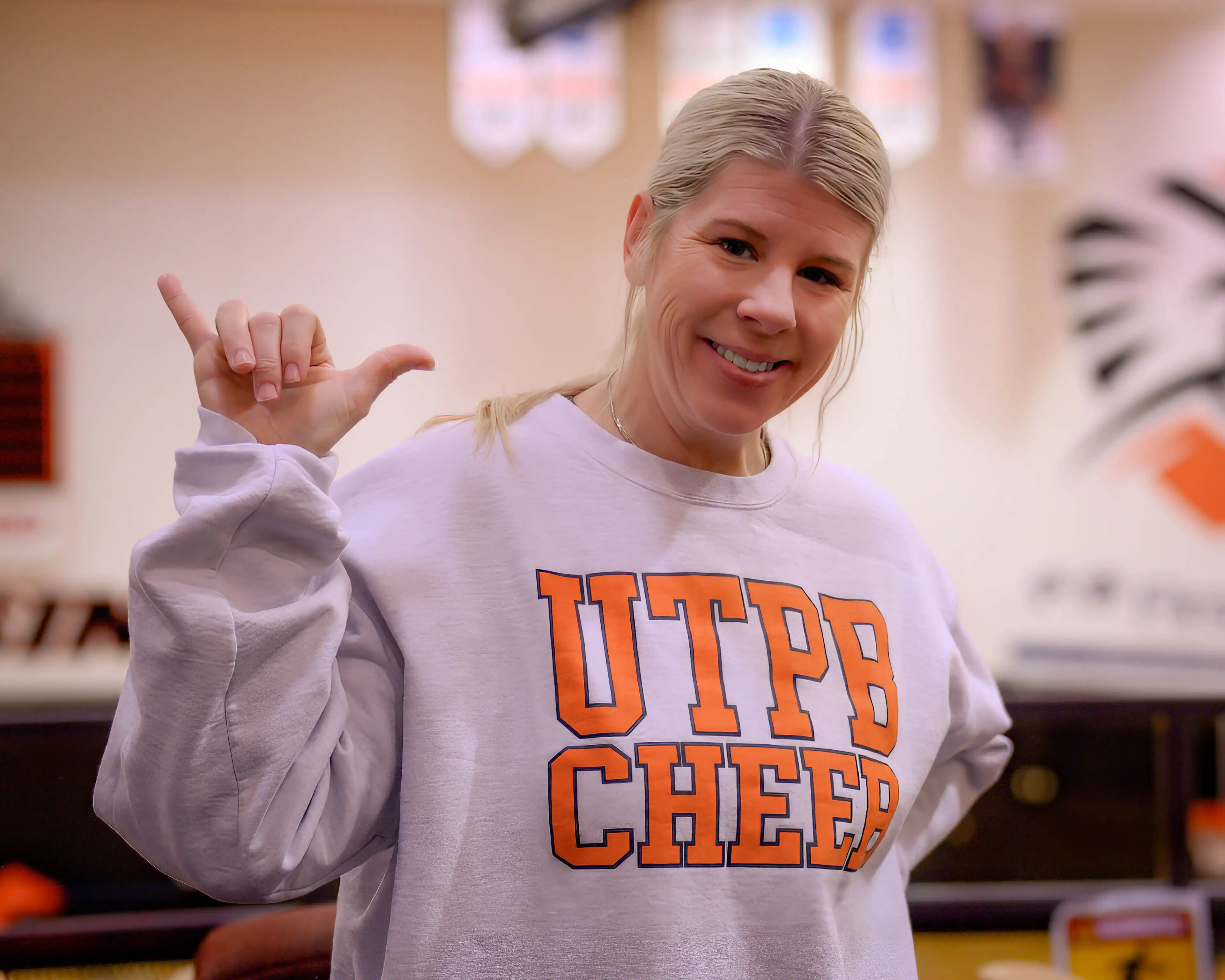 UTPB's Spirit Coordinator, Terry Lynn Lane, holding Falcons Up in the UTPB gym.