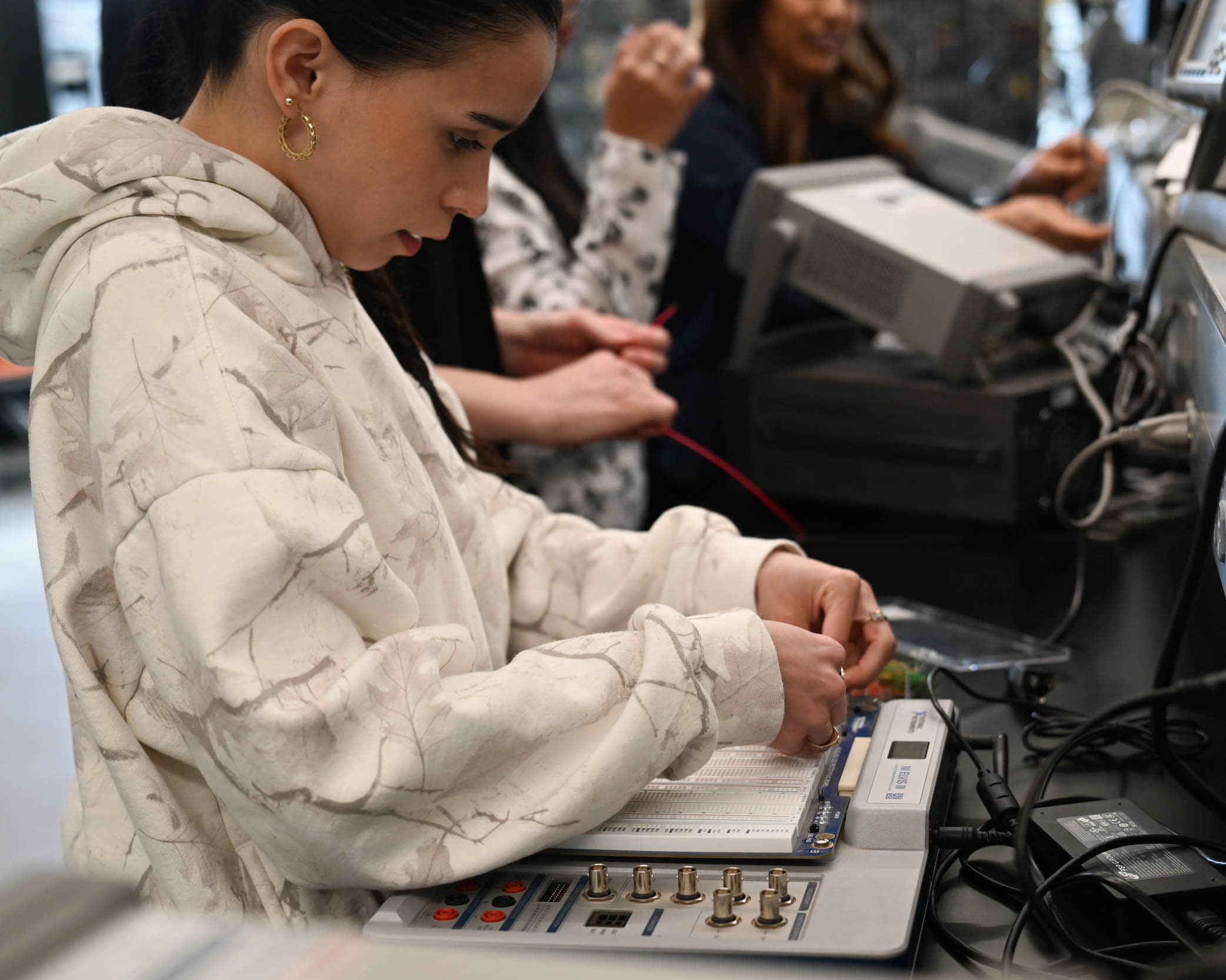 A student in the Society for Women Engineers organization learning how to plug in wires to an electrical breadboard to create circuits. 