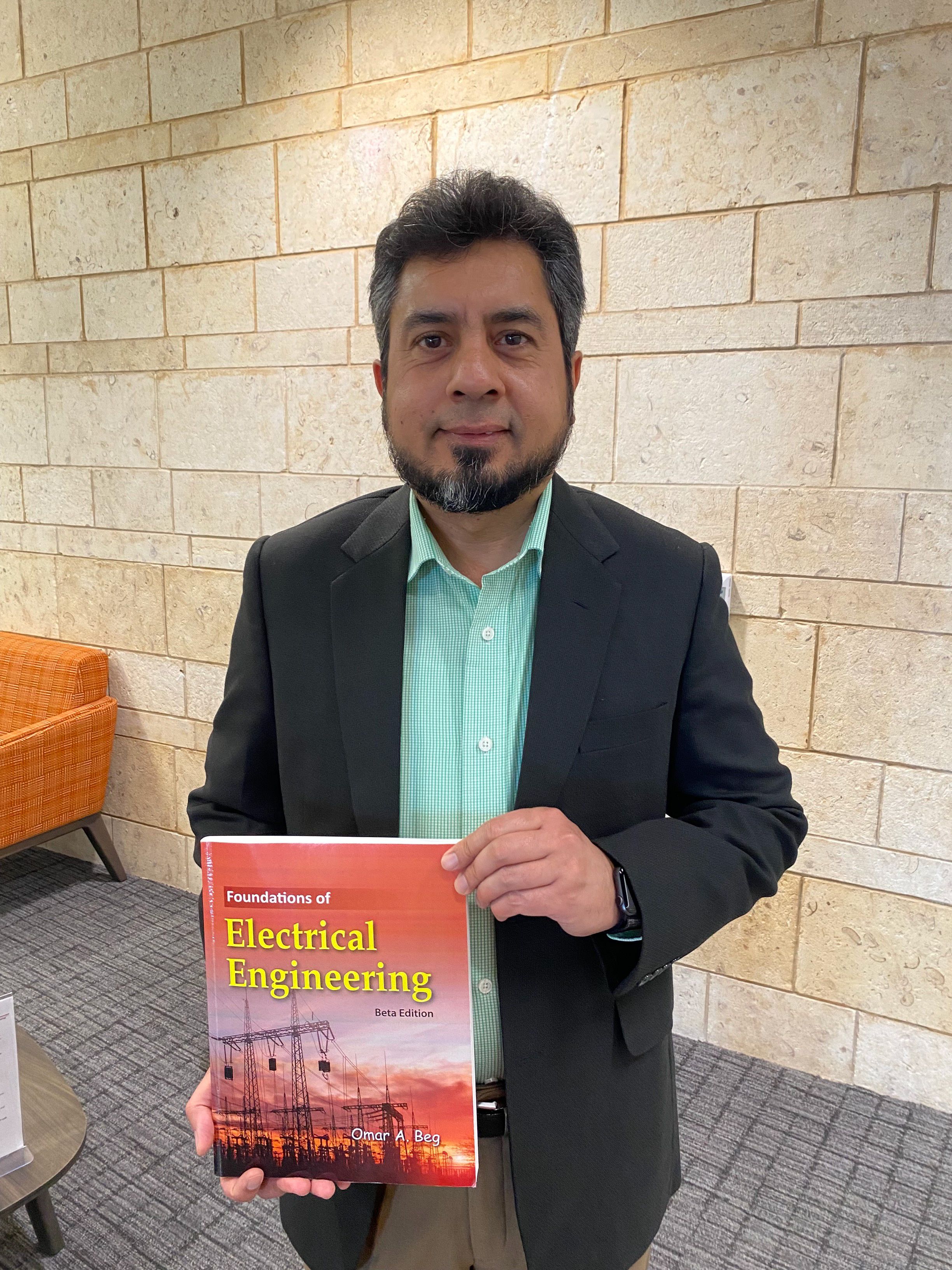 Dr. Omar Beg con libro en edificio de ingeniería