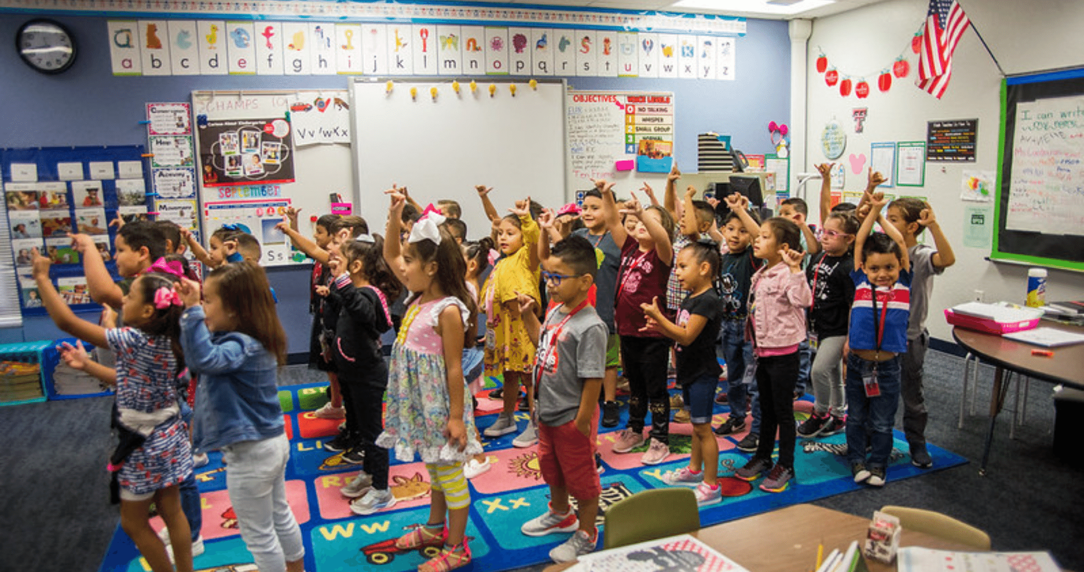 Kinder students raising hands in classroom