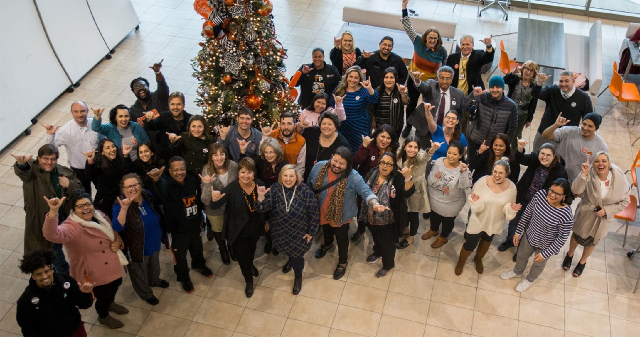 First generation students, faculty, and staff smile for picture with their falcons up