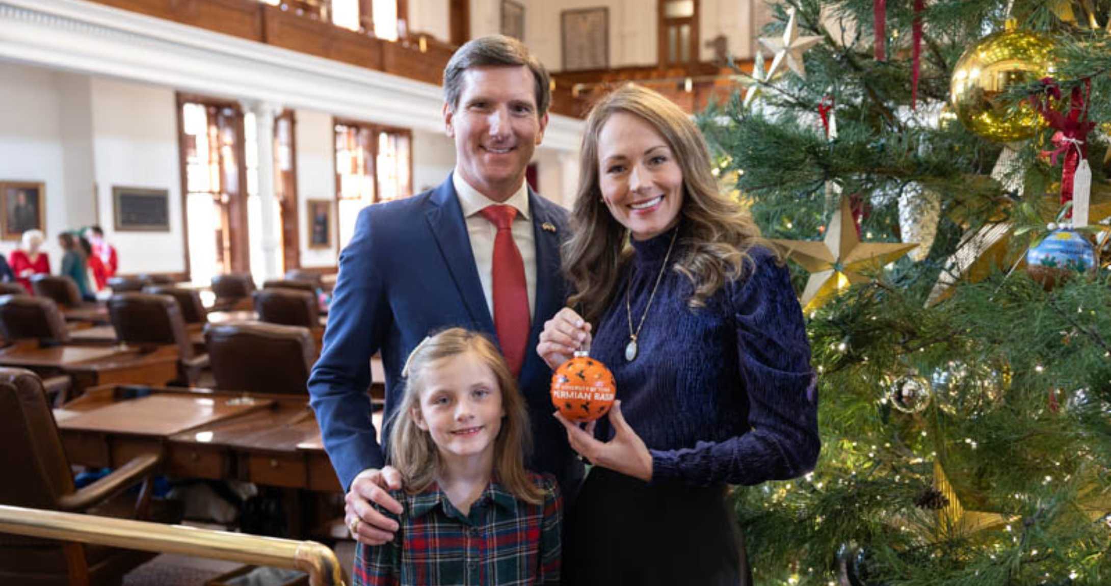 Landgraf family holding ornament in front of tree
