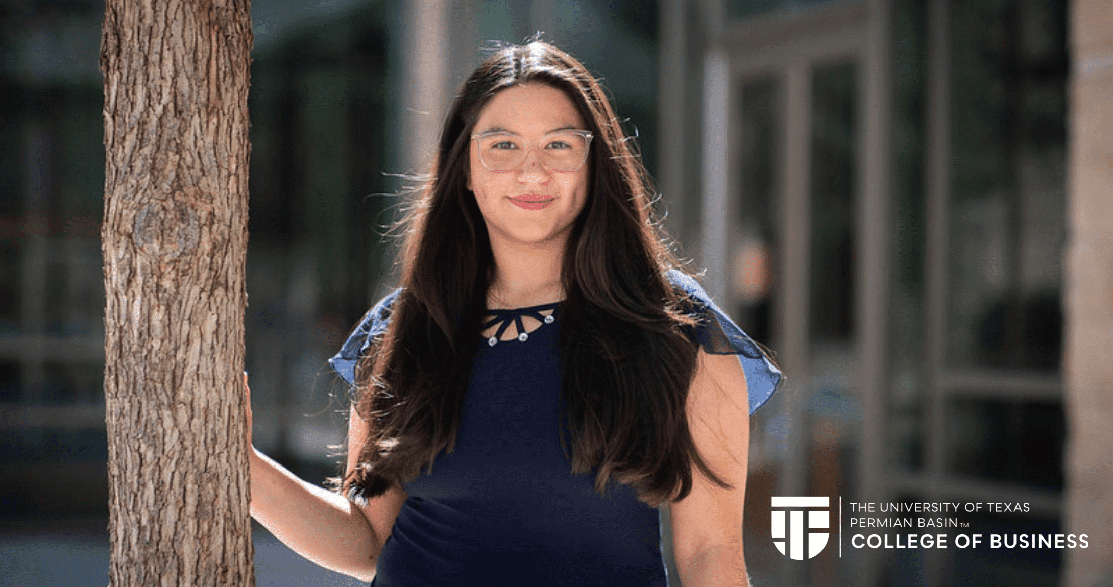 student posing next to a tree