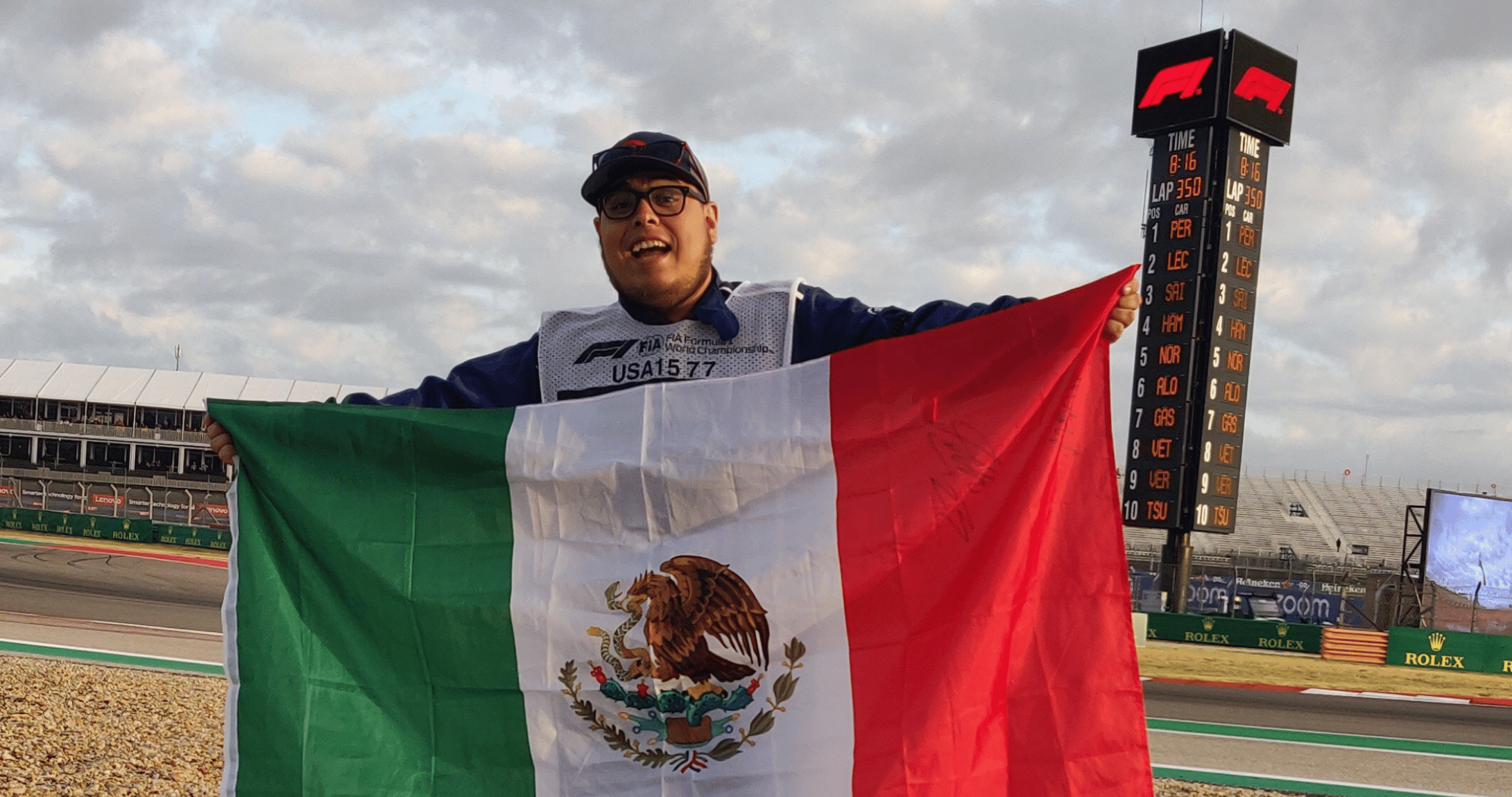 student holding up Mexico flag in front of racetrack